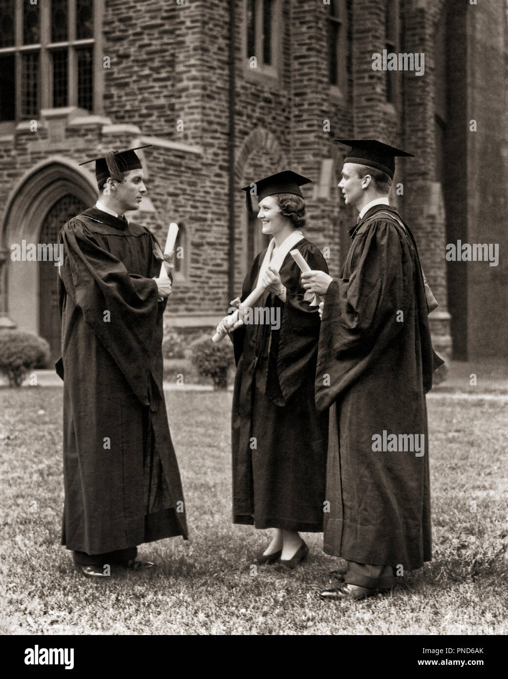 1930s 1940s GRUPPE HOCHSCHULABSOLVENTEN EINE FRAU zwei Männer tragen MORTARBOARD CAPS HÜTE UND KLEIDER HOLDING DIPLOME REDEN - s 6203 HAR 001 HARS FREUDE LIFESTYLE ZUFRIEDENHEIT FEIER FRAUEN KOPIE RAUM VOLLER LÄNGE DAMEN PERSONEN MÄNNER VERTRAUEN ABSOLVENTEN B&W ERFOLG TRÄUME GLÜCK ROBEN SIEG UNIVERSITÄTEN AUFREGUNG WISSEN KLEIDER STOLZ HOCHSCHULBILDUNG CAPS STILVOLLE HOCHSCHULEN MORTARBOARD DIPLOME WACHSTUM MITEINANDER junger erwachsener Mann junger Erwachsener FRAU SCHWARZ UND WEISS KAUKASISCHEN ETHNIE HAR 001 ALTMODISCH Stockfoto