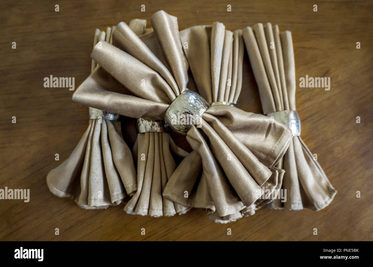 Golden serviette Bogen mit Silber Ring fancy Folding für Urlaub Holz Tisch Hintergrund Stockfoto