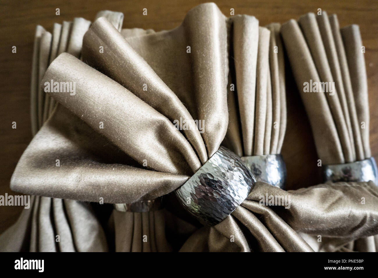 Golden serviette Bogen mit Silber Ring fancy Folding für Urlaub Holz Tisch Hintergrund Stockfoto