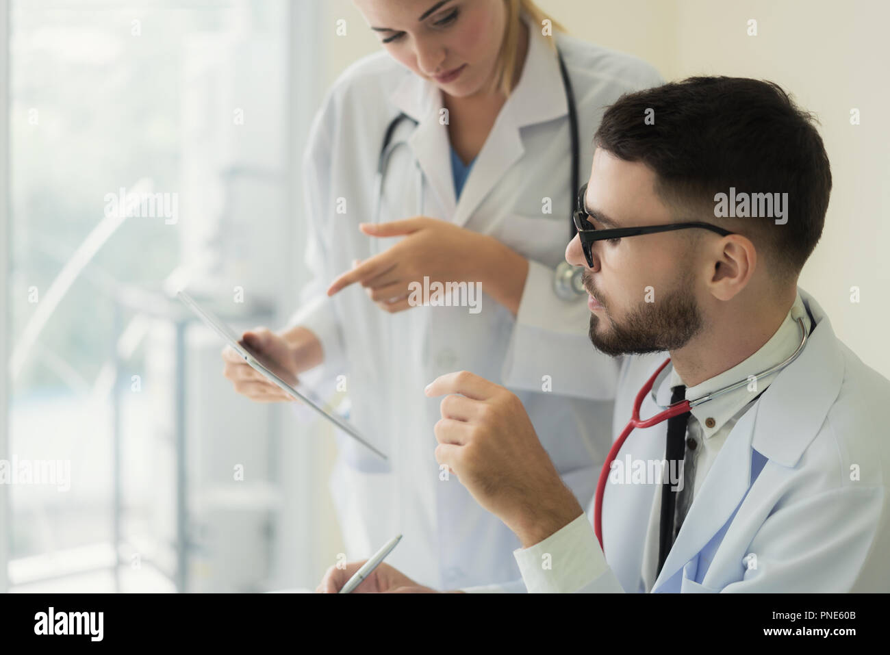 Zwei Doktoren der Analyse und Beratung über medizinische Aufzeichnung im modernen Krankenhaus. Kaukasische Ärzte reden über Bericht. Stockfoto