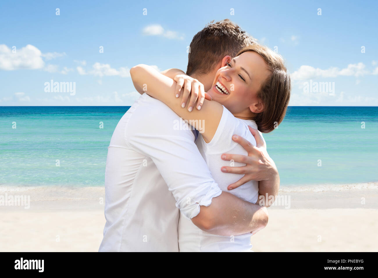 Nahaufnahme einer glücklichen jungen Frau umarmte ihren Mann am Strand Stockfoto