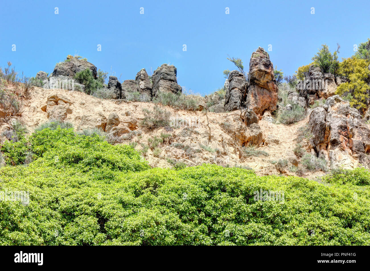 Eine Landschaft der grünen Bäume und Büsche, zusammen mit der roten und braunen Felsen, in der gaël City Park im Frühling, Spanien Stockfoto