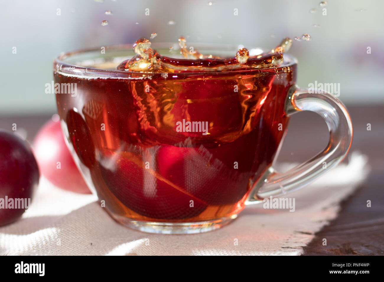 Heißes Getränk. Heiße Früchte Tee in mit Pflaumen. Die Hälfte plum in einer Tasse Tee. Pflaume wurde in eine Tasse Kaffee geworfen Stockfoto