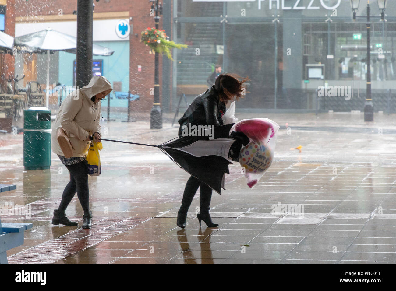 Stadtzentrum Warrington, Cheshire, England, Großbritannien - 21 September 2018 - Wetter - am späten Nachmittag und die Windstärke Winde der Sturm Bronagh, der zweite Sturm der britischen Winter innerhalb von Tagen, erhöhten ihre Intensität, mit Böen von über 50 mph in Warrington, Cheshire. Bild: Menschen kämpfen, um ihre Schirme richtig in den Wind zu halten. Stockfoto