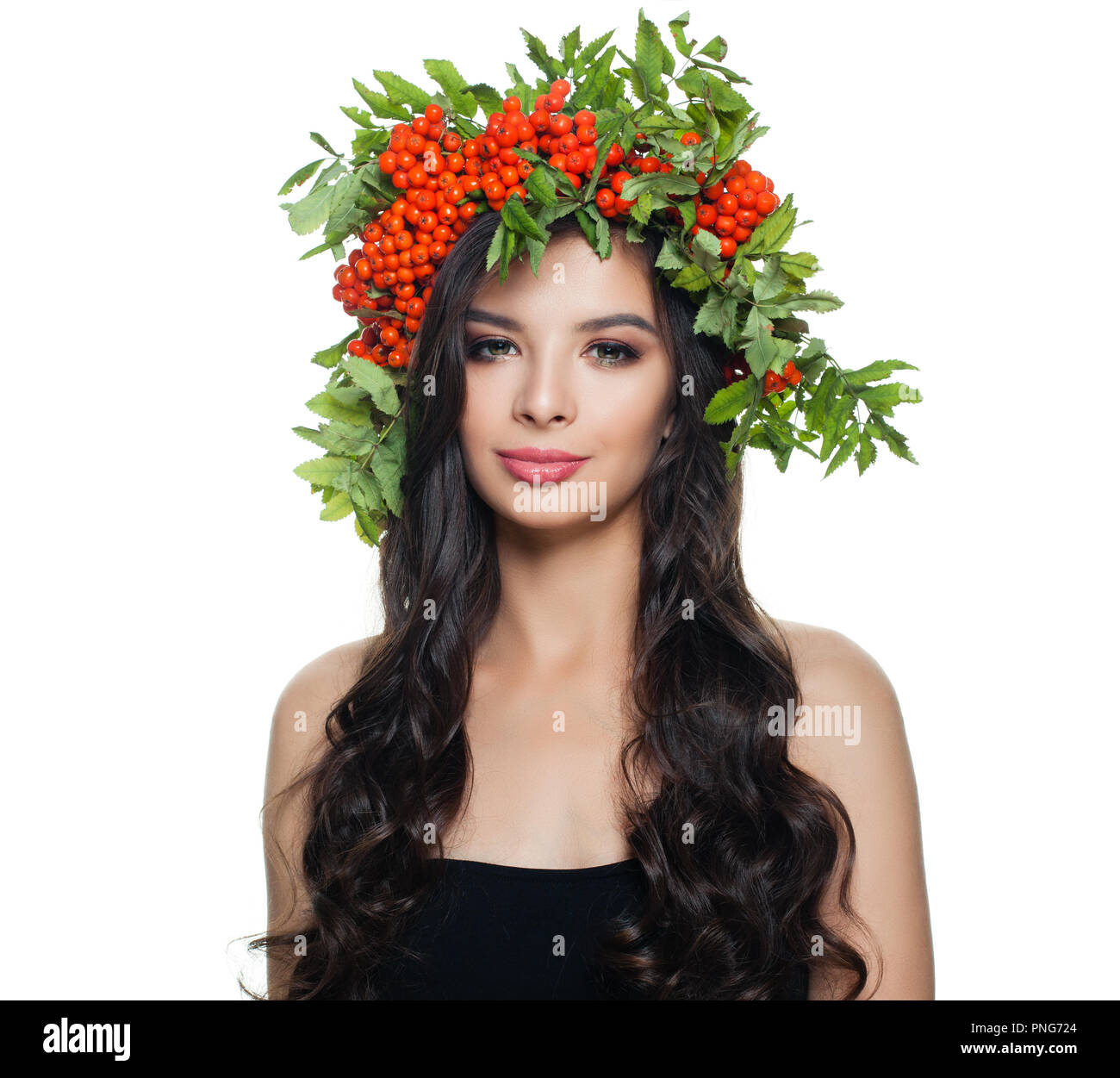 Schöne brünette Frau mit gesunden lockige Haare, natürliches Make up und roten Beeren und grüne Blätter Kranz auf weißem Hintergrund Stockfoto