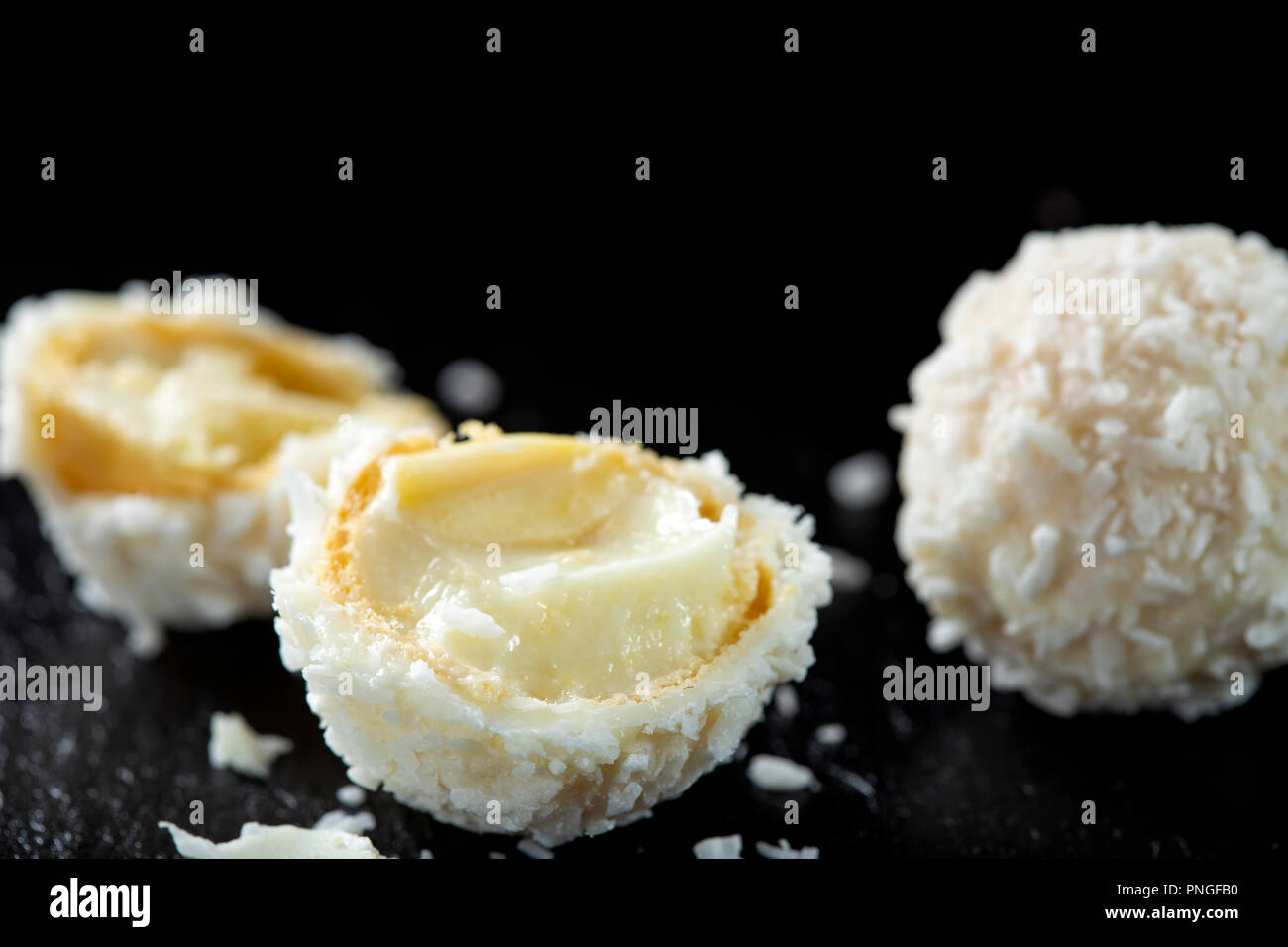 In der Nähe von Broken white Candy mit Kokosraspeln und weiße Schokolade Creme auf dunklem Schiefer Stockfoto