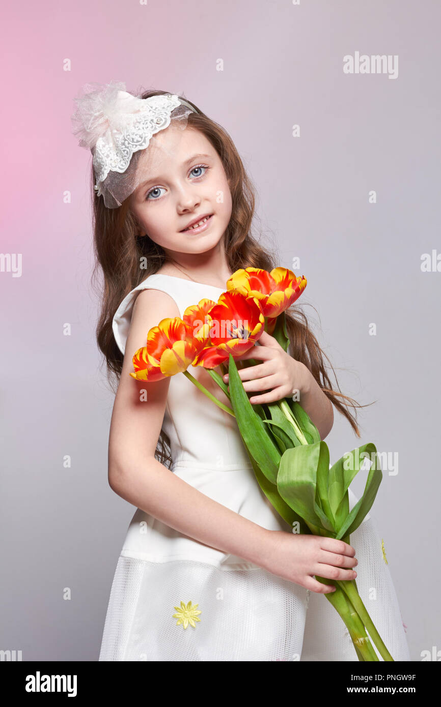 Mädchen mit großen blauen anime Augen und einem Blumenstrauß aus Tulpen Blumen in den Händen. World's Mutter, Tag Frühling, Frühling Blumenstrauß in der Hand des Kindes. L Stockfoto