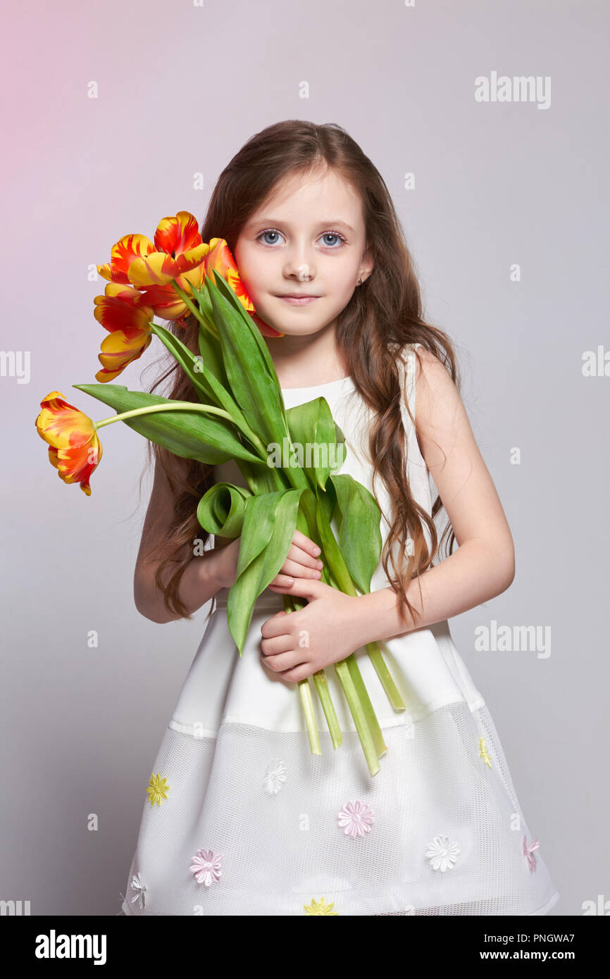 Mädchen mit großen blauen anime Augen und einem Blumenstrauß aus Tulpen Blumen in den Händen. World's Mutter, Tag Frühling, Frühling Blumenstrauß in der Hand des Kindes. L Stockfoto