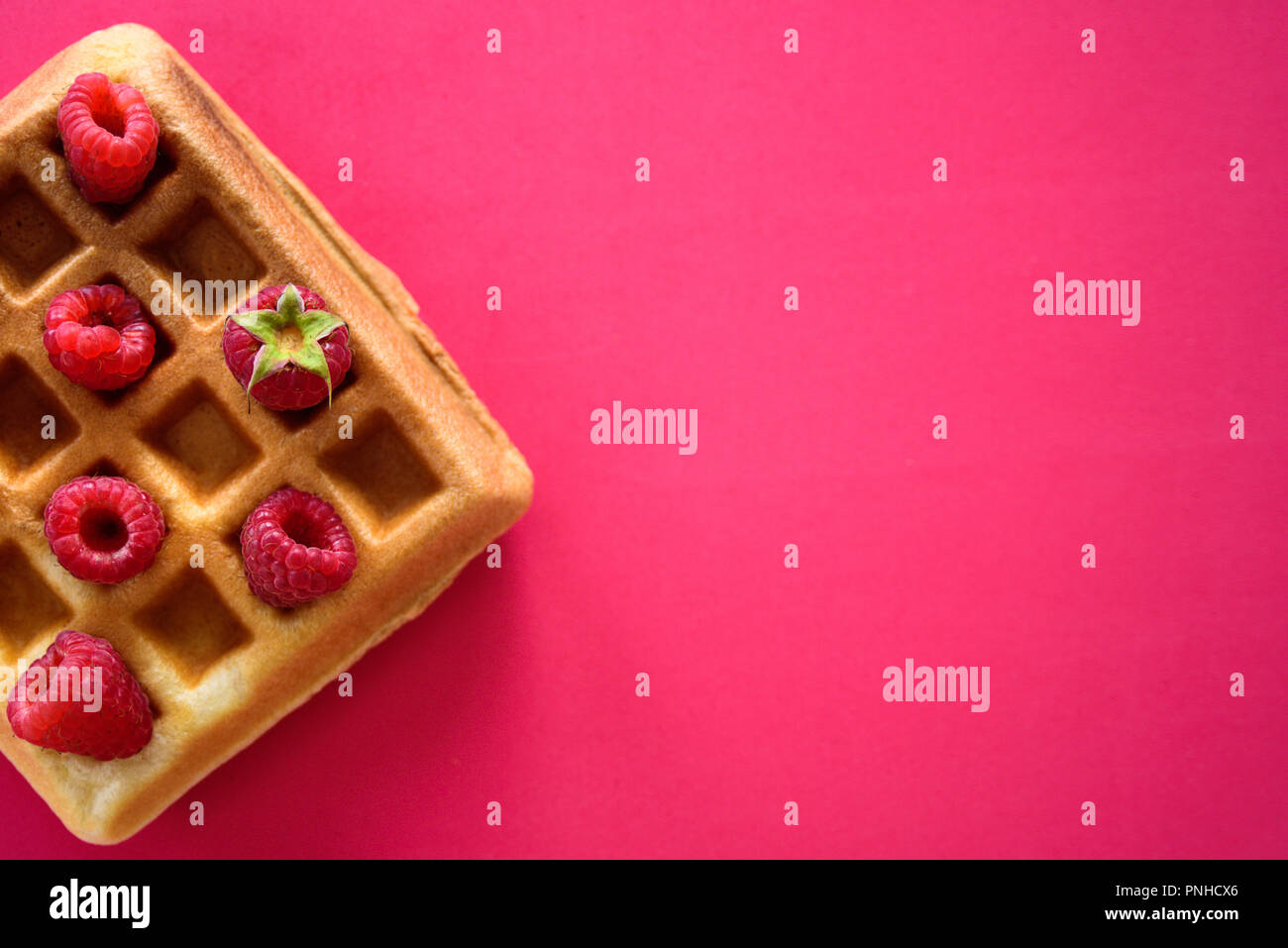 Belgische Waffeln mit Himbeeren auf rotem Hintergrund Stockfoto