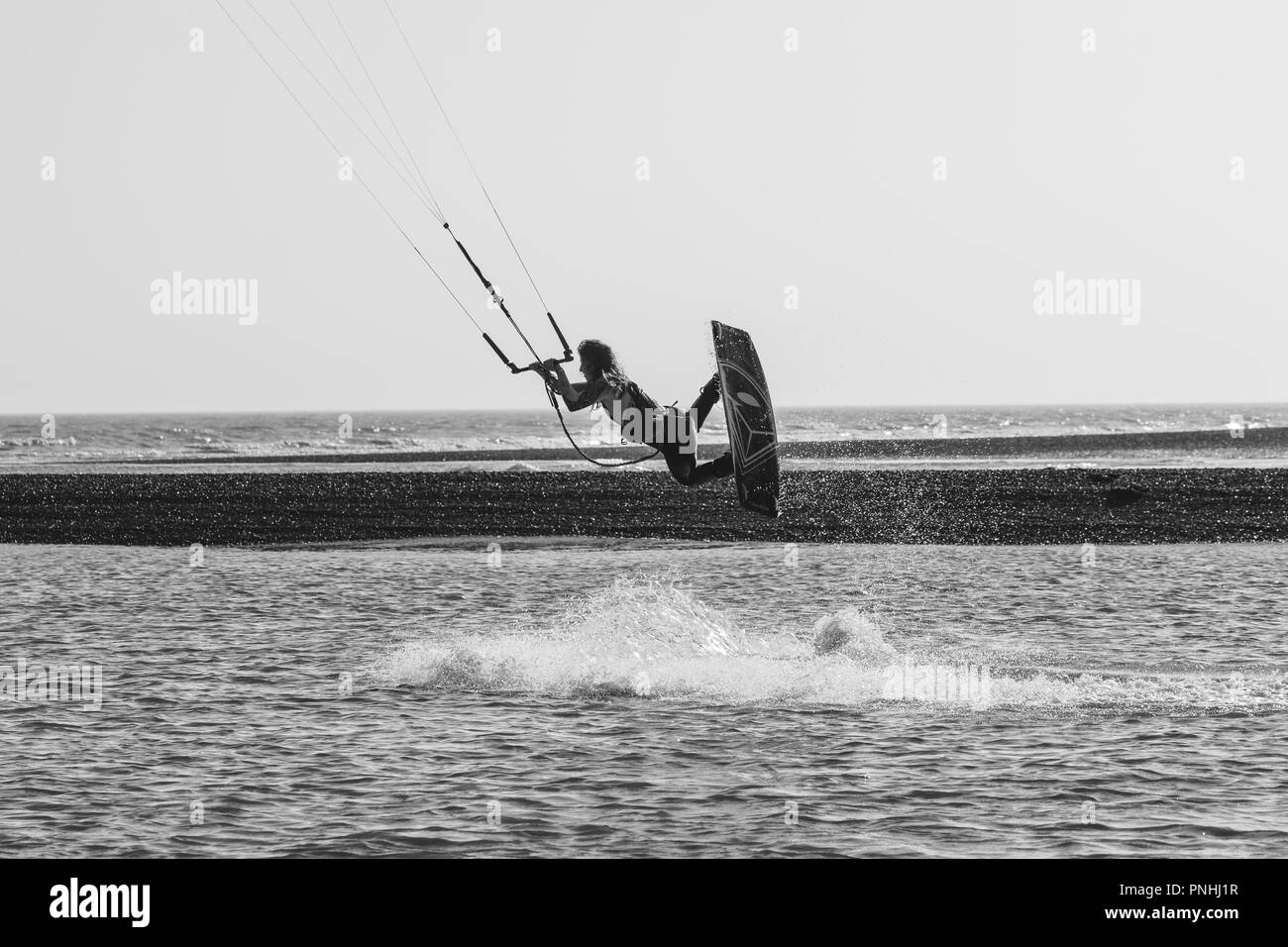 Kiteboarder tricks ziehen und Luft an einem hellen Sommertag mit perfekt klaren blauen Himmel. Schindel Strret, Suffolk, Großbritannien Stockfoto