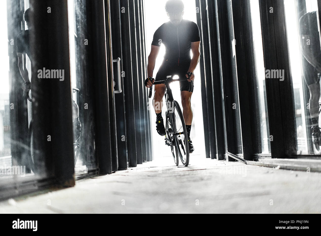 Sport bike Mann reiten in städtischen gläserne Tunnel mit Licht. Stockfoto