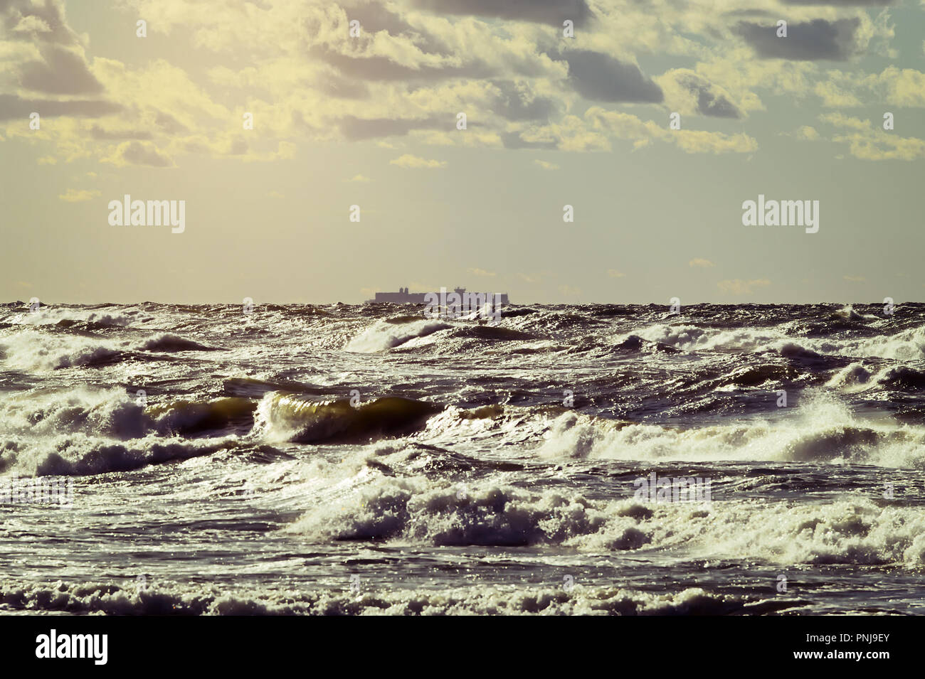 Frachtschiff Silhouette am Horizont. Große Container schiff Segeln durch die stürmischen Wellen der Ostsee. Die Danziger Bucht, Pommern, Polen. Stockfoto