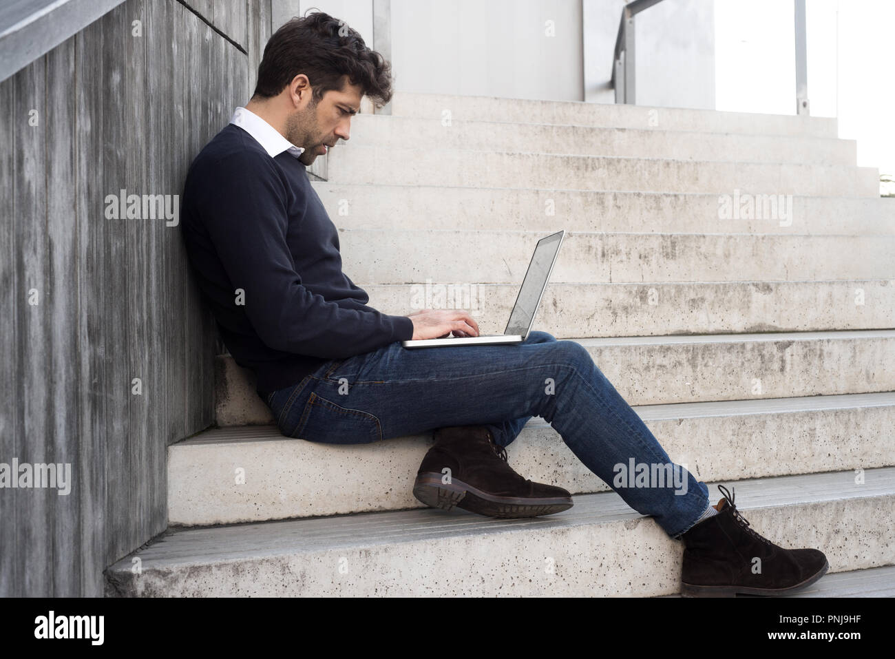 Junger Mann mit Computer in Treppe Stockfoto