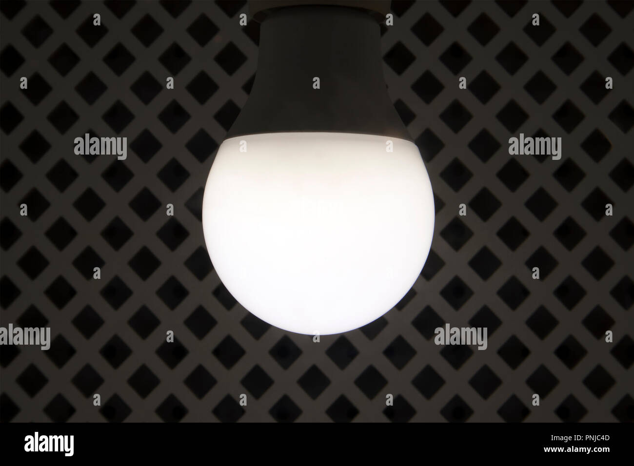 Moderne, energiesparende Lampe gegen rhombed Gitter Hintergrund Stockfoto