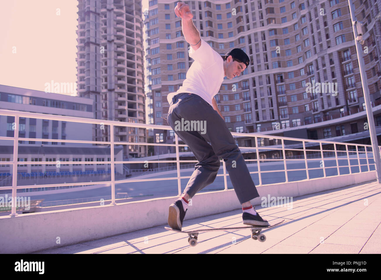 Aktive junge Mann demonstriert seine Übungen auf Skateboard Stockfoto