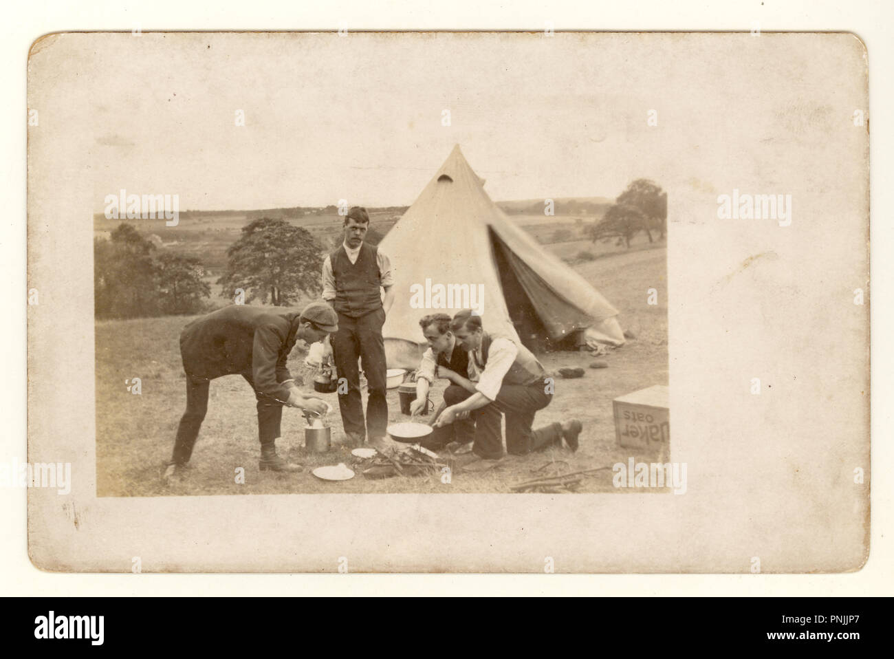 Edwardian Postkarte von jungen Männern Camping in der Natur, Kochen auf offenem fireout außerhalb der Leinwand Zelt, circa 1904, Großbritannien Stockfoto