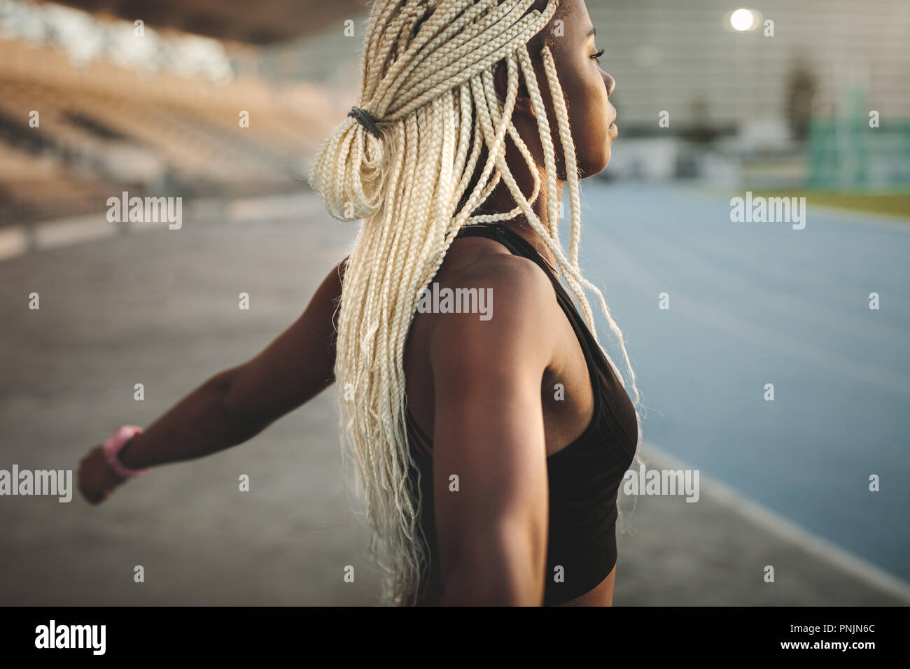 Seitenansicht einer Sportlerin, Übung in einem Leichtathletik Stadion. Athlet Aufwärmen vor einem Lauf ihre Hände recken sich in einem Stadion. Stockfoto