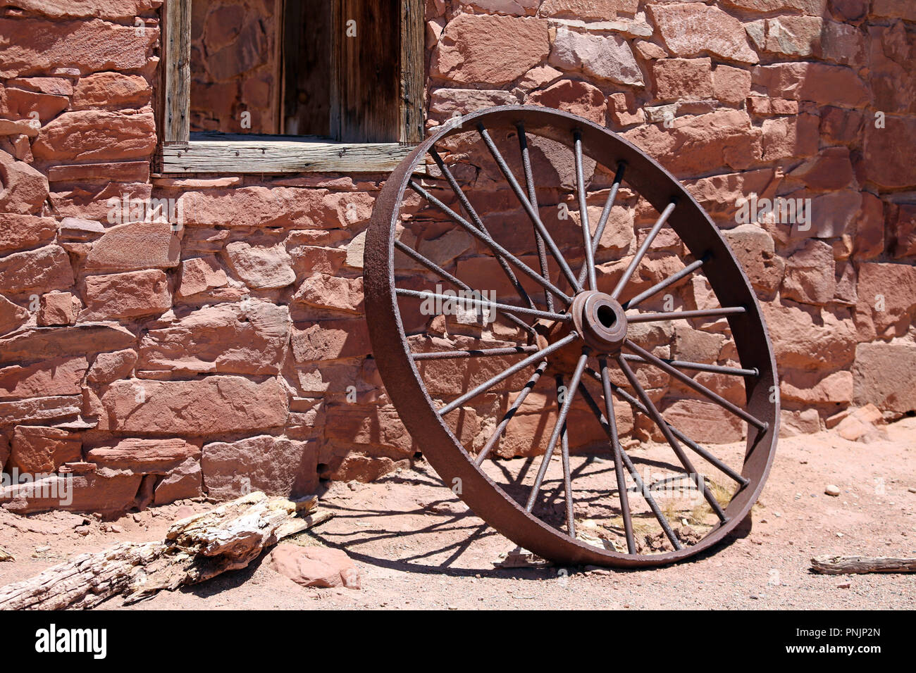 Alte rostige Bügeleisen Rad gelehnt aus rotem Sandstein Mauer der historischen Struktur Stockfoto