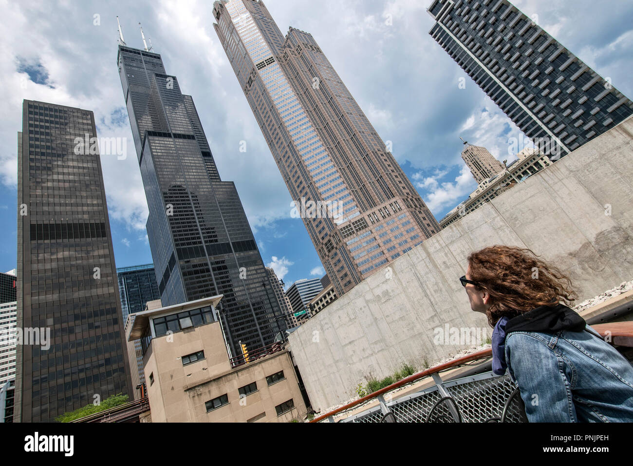 Frau suchen Bei Willis Tower und anderen Wolkenkratzern aus ein Boot auf dem Chicago River, in der Innenstadt von Chicago, IL. Stockfoto