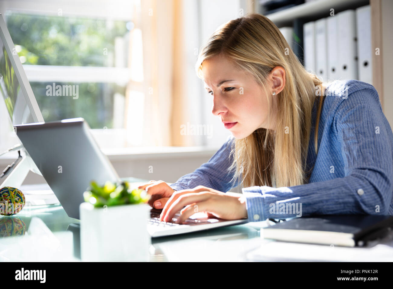 Konzentrierte Junge Geschäftsfrau mit Laptop am Arbeitsplatz Stockfoto