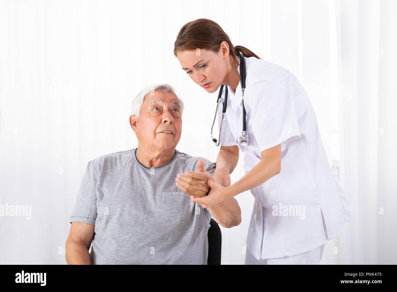 Junge Ärztin Prüfung von männlicher Patient Puls in der Klinik Stockfoto Junge Ärztin Prüfung von männlicher Patient Puls in der Klinik Stockfoto