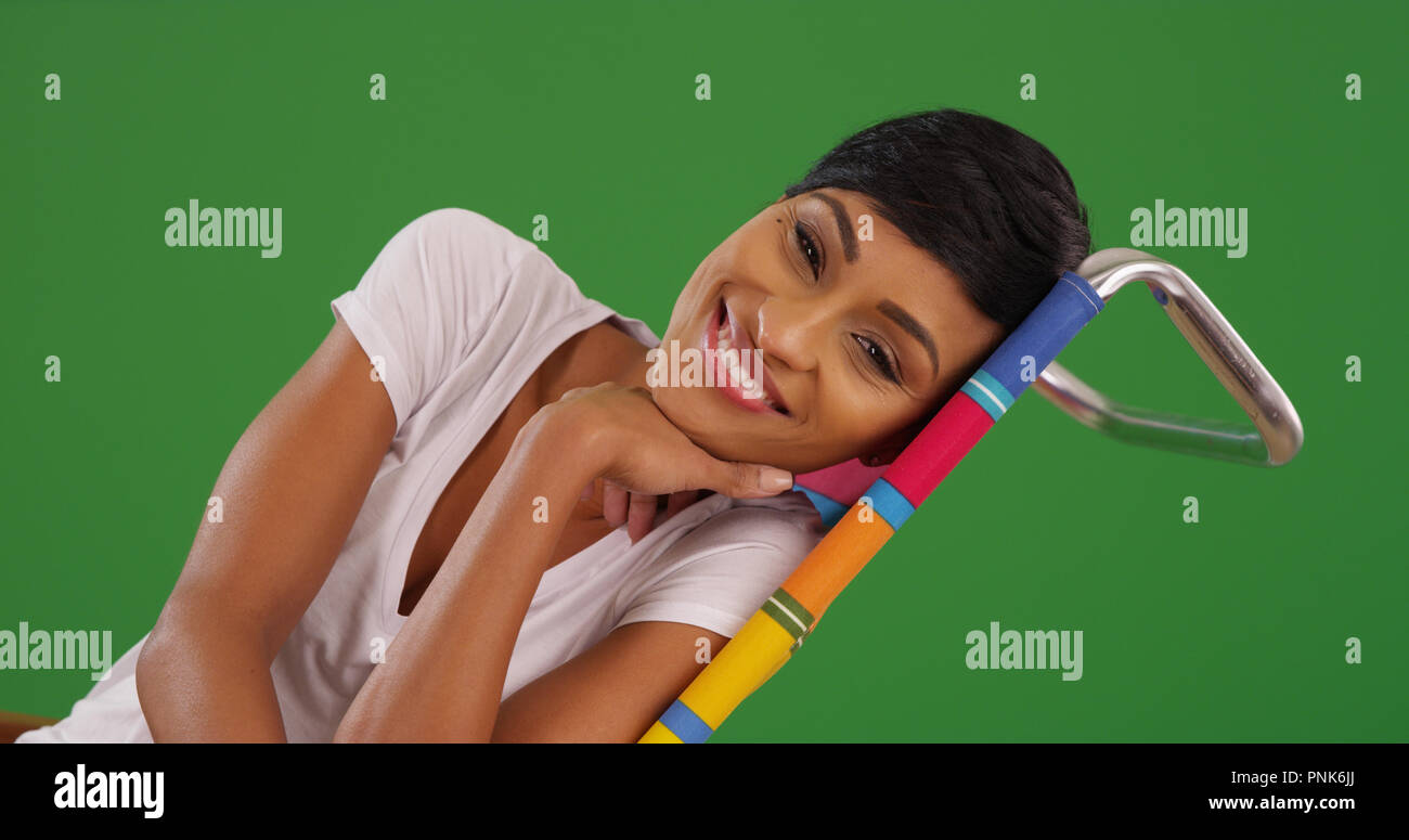 Junge schwarze Frau an der Kamera liegen Lächeln am Strand Stuhl auf Green  Screen Stockfotografie - Alamy