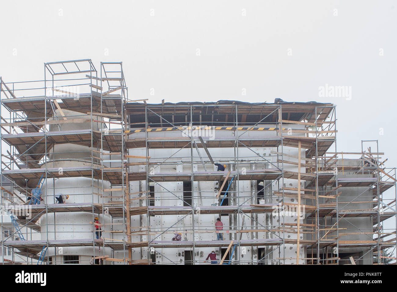 Professionelle Bauarbeiter auf dem Gerüst Aufzug gedämmten Wand Fassade mit Mineralwolle. Dachdecker tragen Gurt isolierende Wand fac Stockfoto