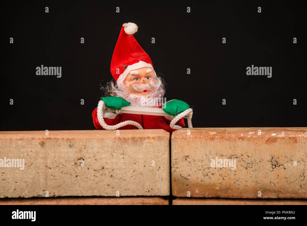 Santa Versuch, die Wand ein zuwanderungskonzept zu klettern Stockfoto