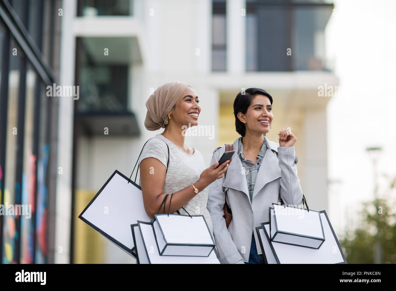 Muslimische Freunde mit einem Smartphone auf Shopping-Tour Stockfoto