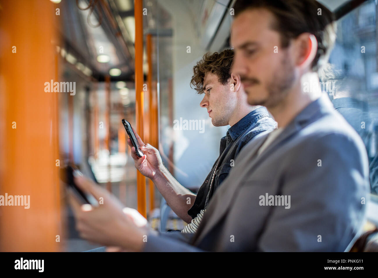 Pendler mit Smartphone auf Zug Stockfoto