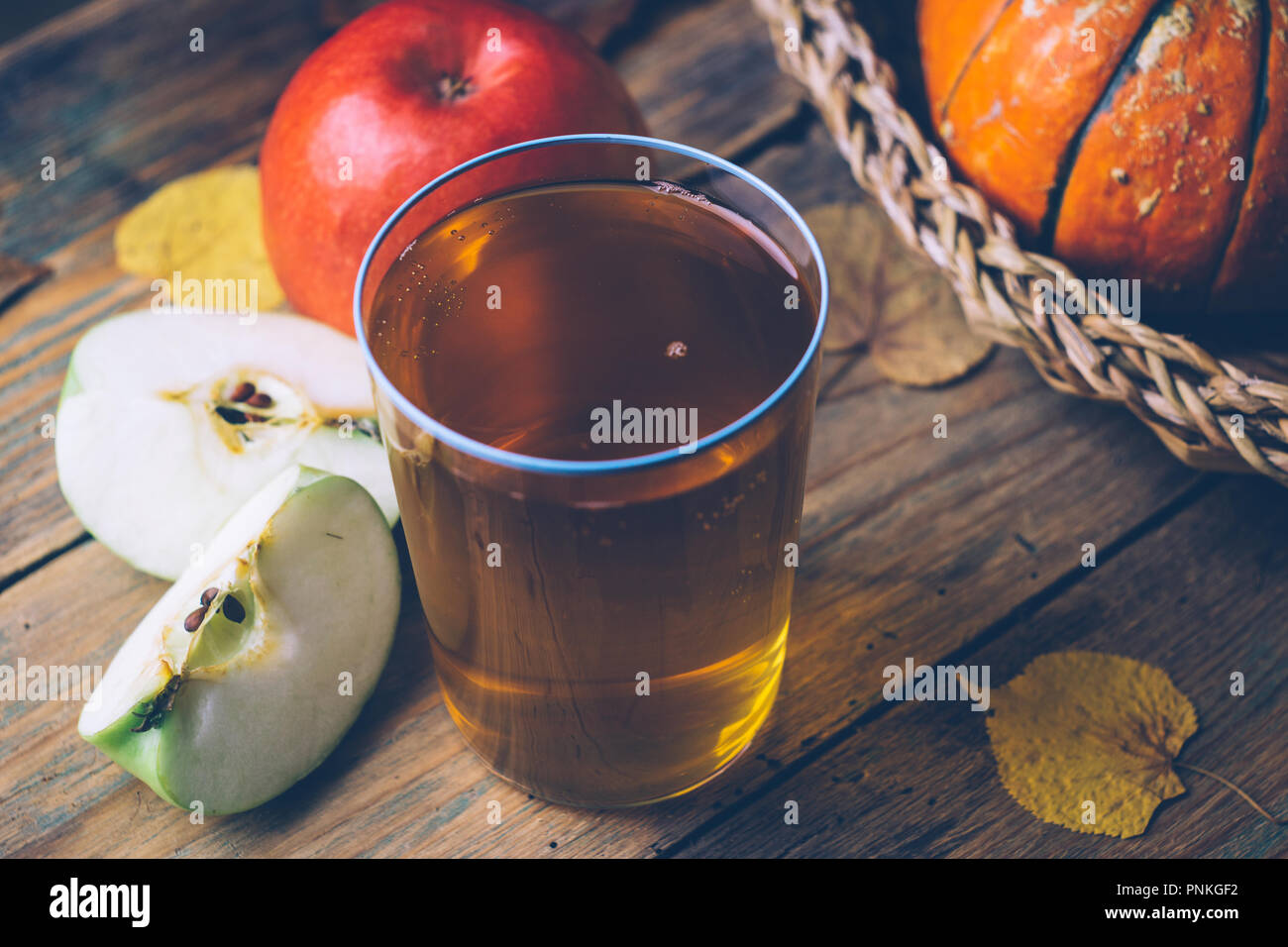 Kalte Apfelwein oder Apfelsaft mit frischen Äpfeln auf einem hölzernen Hintergrund. Herbst Getränke. Herbstliche Stimmung Stockfoto