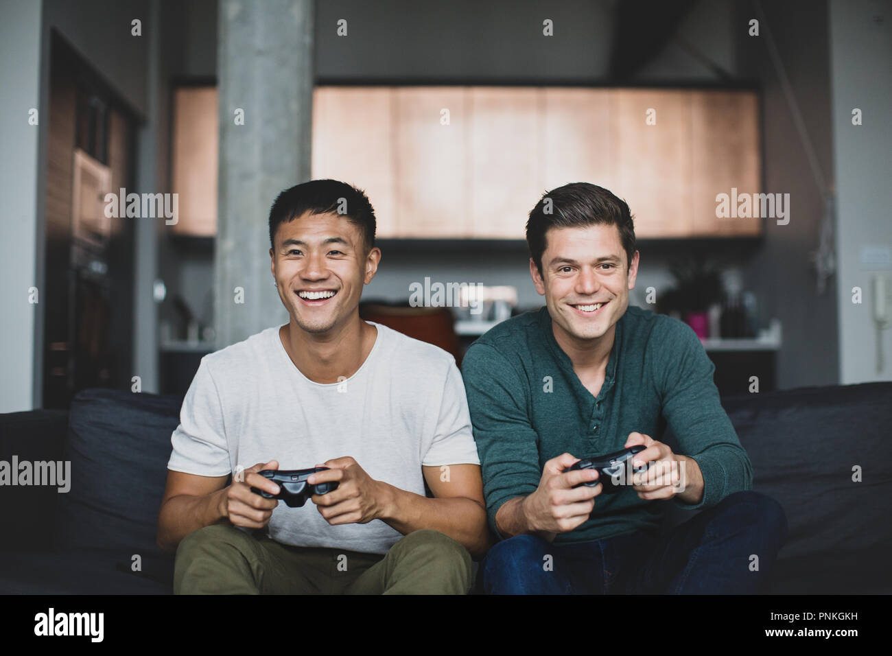 Männliche Freunde spielen auf einer Spielekonsole Stockfoto
