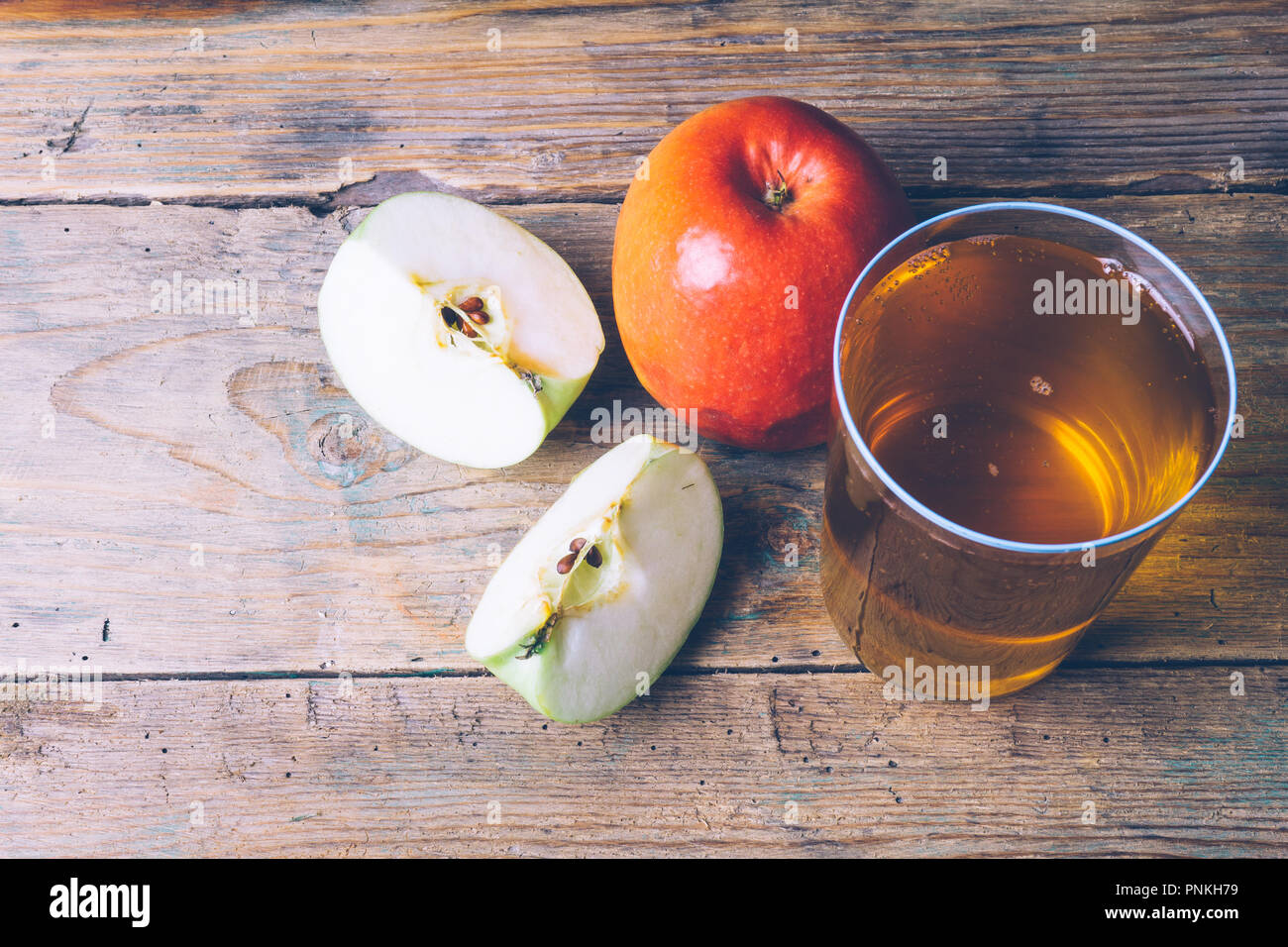 Kalte Apfelwein oder Apfelsaft mit frischen Äpfeln auf einem hölzernen Hintergrund. Herbst Getränke. Herbstliche Stimmung Stockfoto