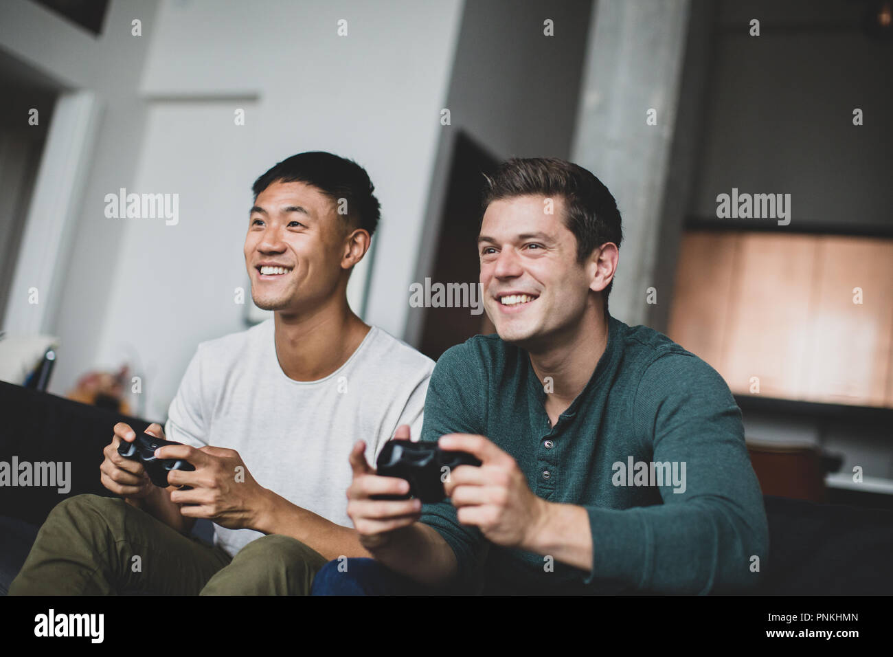 Männliche Freunde spielen auf einer Spielekonsole Stockfoto
