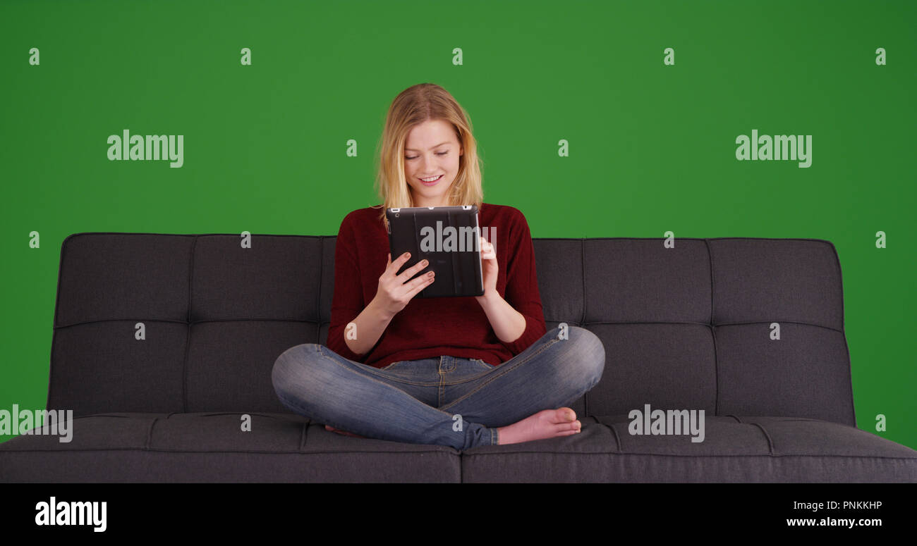 Tausendjährige entspannt auf einem Sofa im Internet surfen mit digitalen Tablette auf Green Screen Stockfoto