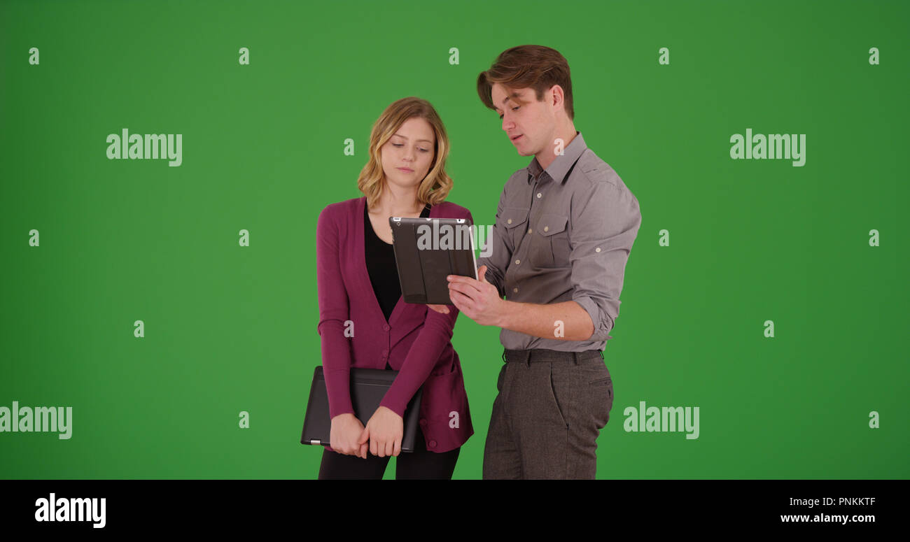 Erfolgreicher Geschäftsmann mit weiblichen Kollegen etwas auf Green Screen Stockfoto