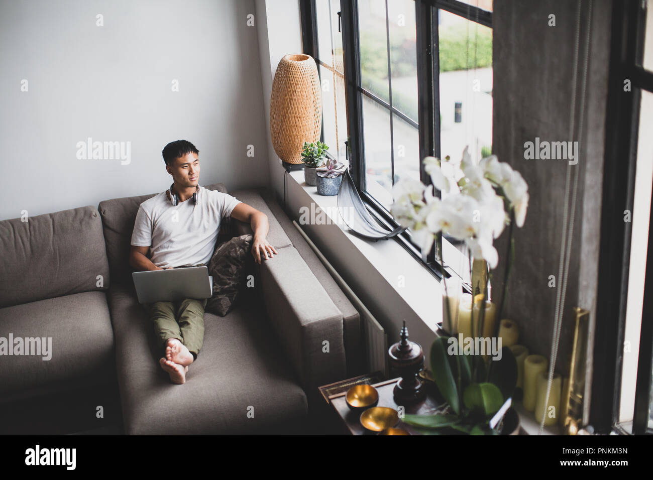 Jungen erwachsenen Asiatischen männlichen Blick aus Apartment Fenster Stockfoto