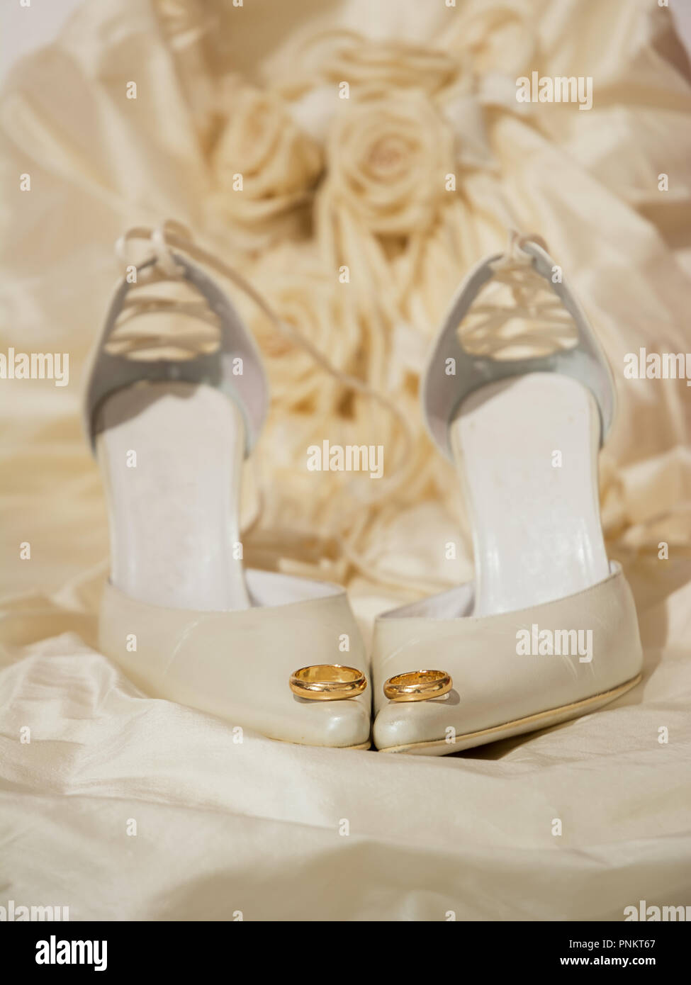 Trauringe und Damenschuhe mit einem Kleid auf dem Hintergrund Stockfoto