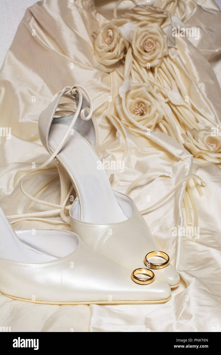 Trauringe und Damenschuhe mit einem Kleid auf dem Hintergrund Stockfoto