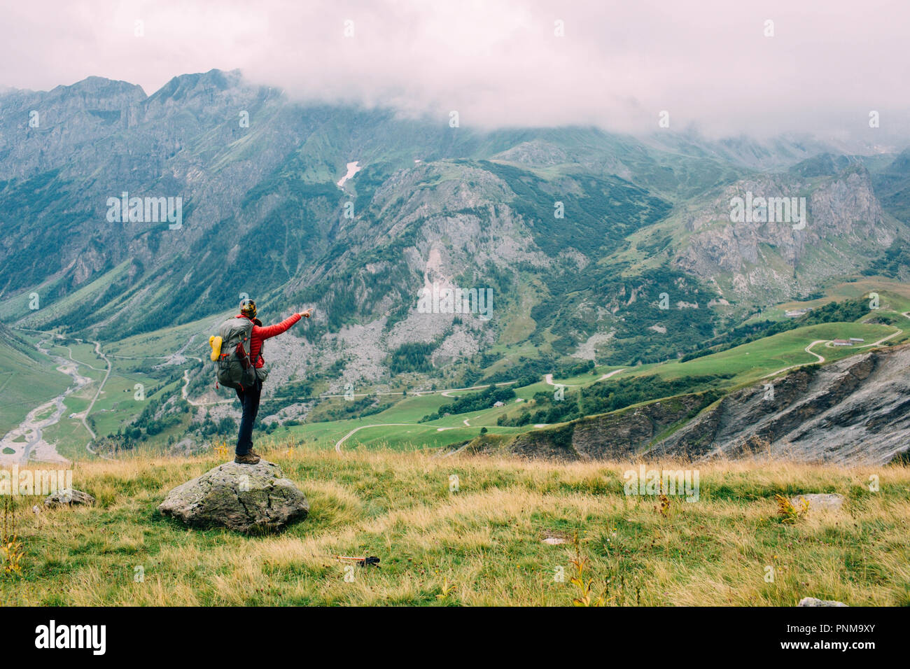 Eine Frau mit einem Rucksack, mit Blick auf das Tal. Wandern rund um den Mont Blanc, Frankreich, Alpen Stockfoto
