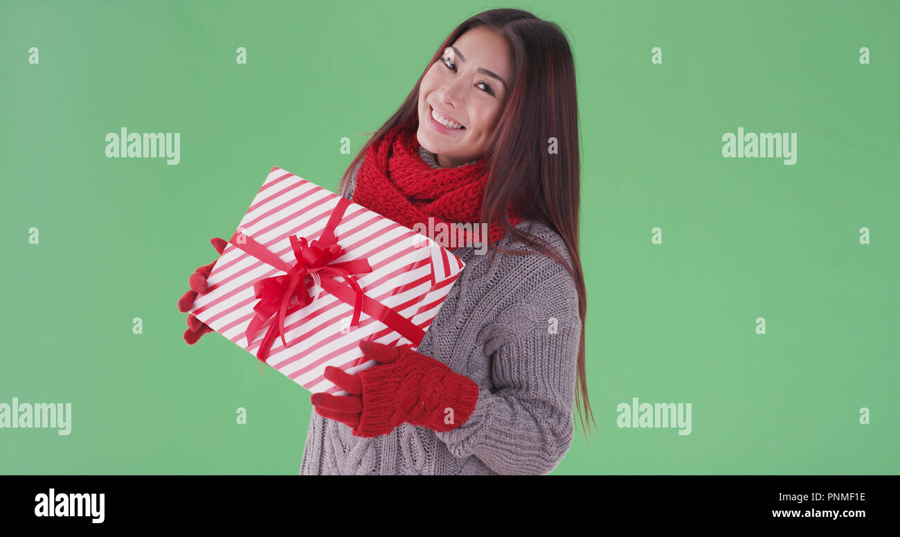 Happy asian woman holding präsentiert im Schnee auf Green Screen Stockfoto