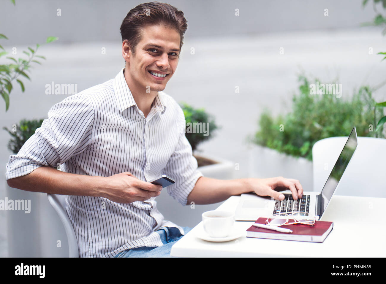 Smart Haltung. Positive stattlicher Mann mit einem Laptop und Sitzen im Cafe beim Surfen im Internet. Stockfoto