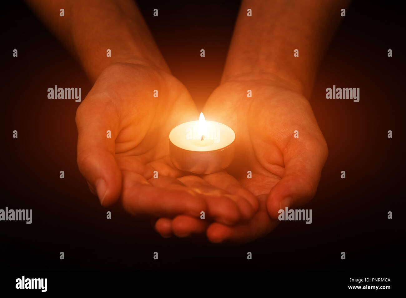 Hände halten und Schützen von leuchtenden leuchtet oder brennende Kerze Kerzenlicht auf die Dunkelheit. Schwarzen Hintergrund. Konzept für Gebet, Beten, hoffen, Vigil, Nacht Stockfoto