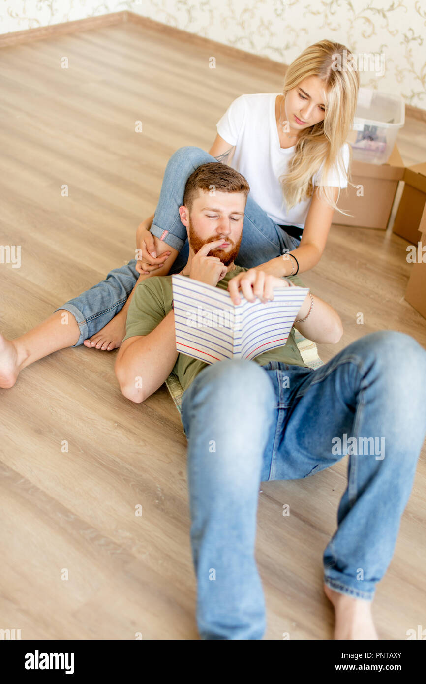 Paar mit Buch sitzen auf dem Bett, während sich in die neue Startseite Stockfoto