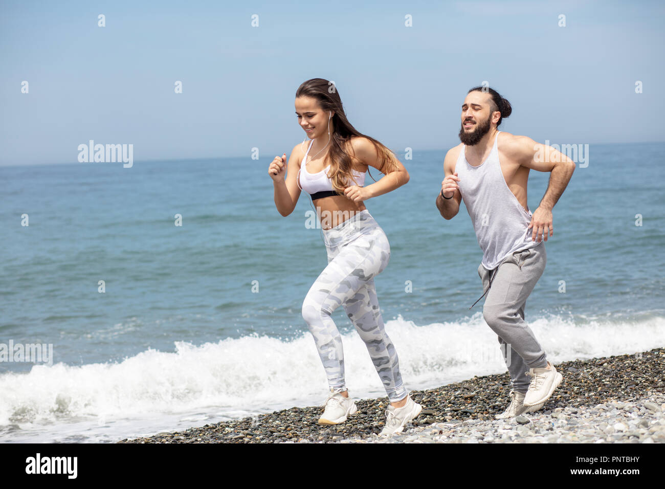 Glückliches Paar zusammen neben dem Wasser läuft am Strand Stockfoto