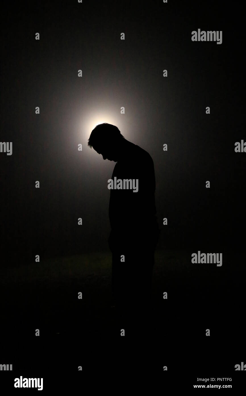 Silhouette in den Dunklen, Leiter lehnte sich nach vorne mit Licht hinter Stockfoto