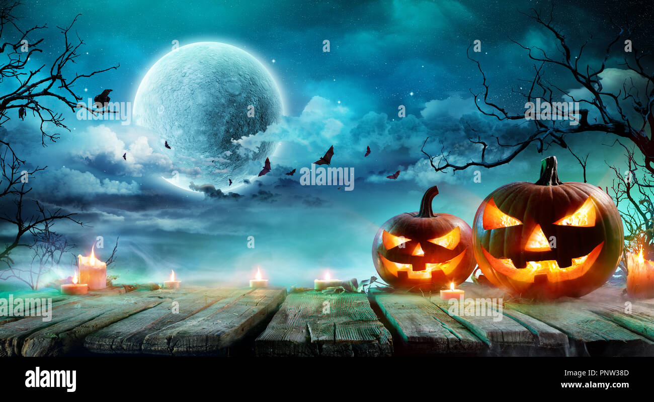 Halloween - Jack O'Lanterns und Kerzen auf dem Tisch in der nebligen Nacht Stockfoto