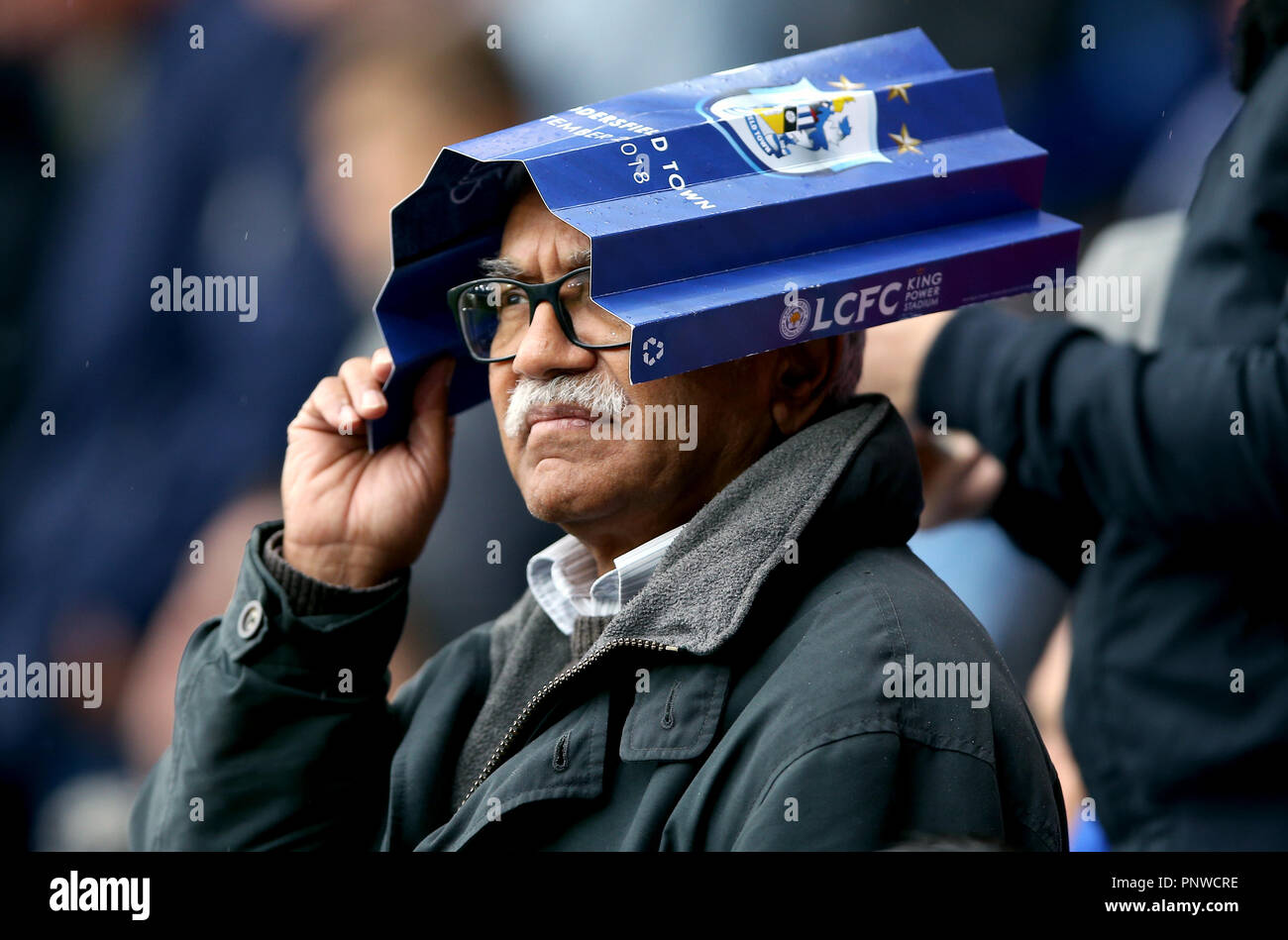 Ein Fan auf der Tribüne verwendet eine Leicester City Broschüre Zuflucht, um sich von der Regen während der Premier League Match für die King Power Stadion, Leicester. Stockfoto