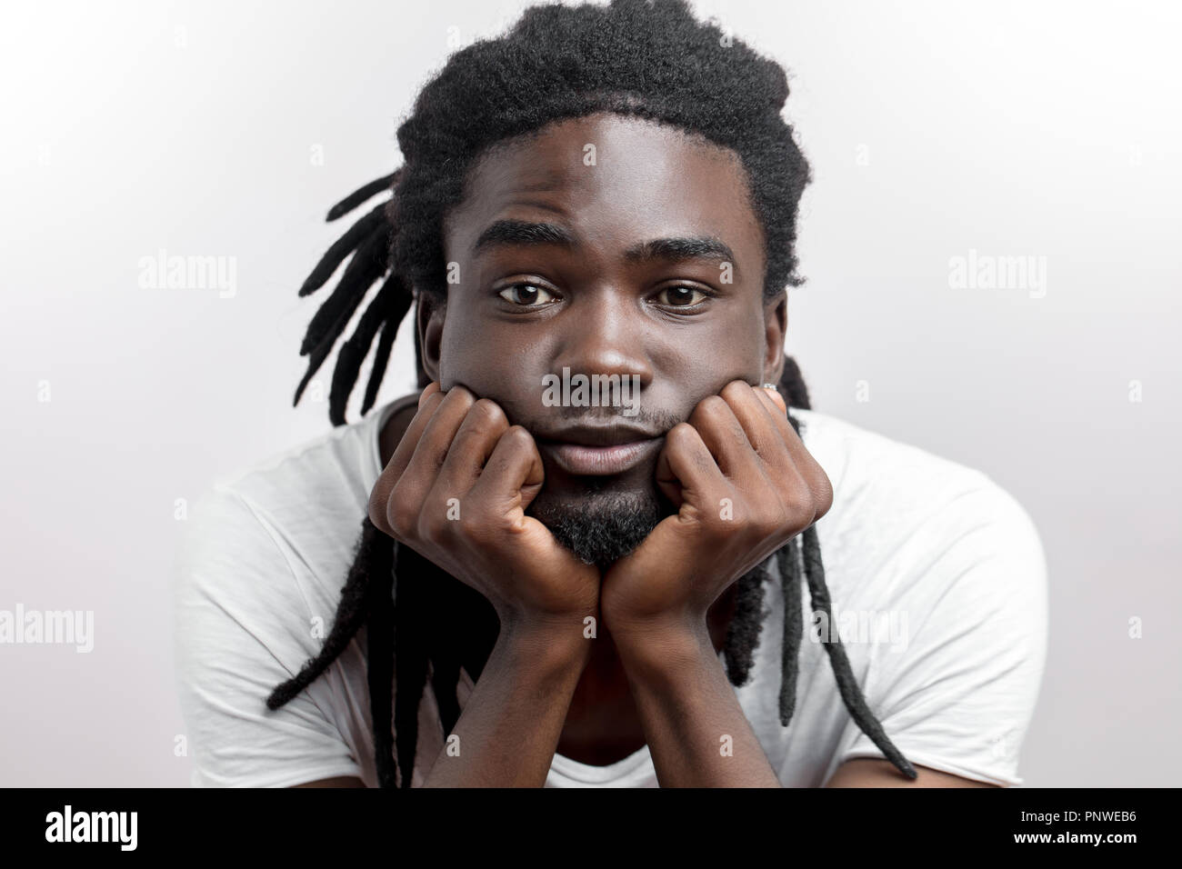 Unglücklich ernsthafte junge afrikanische amerikanische mit Dreadlocks stützt den Kopf auf die Hände Stockfoto