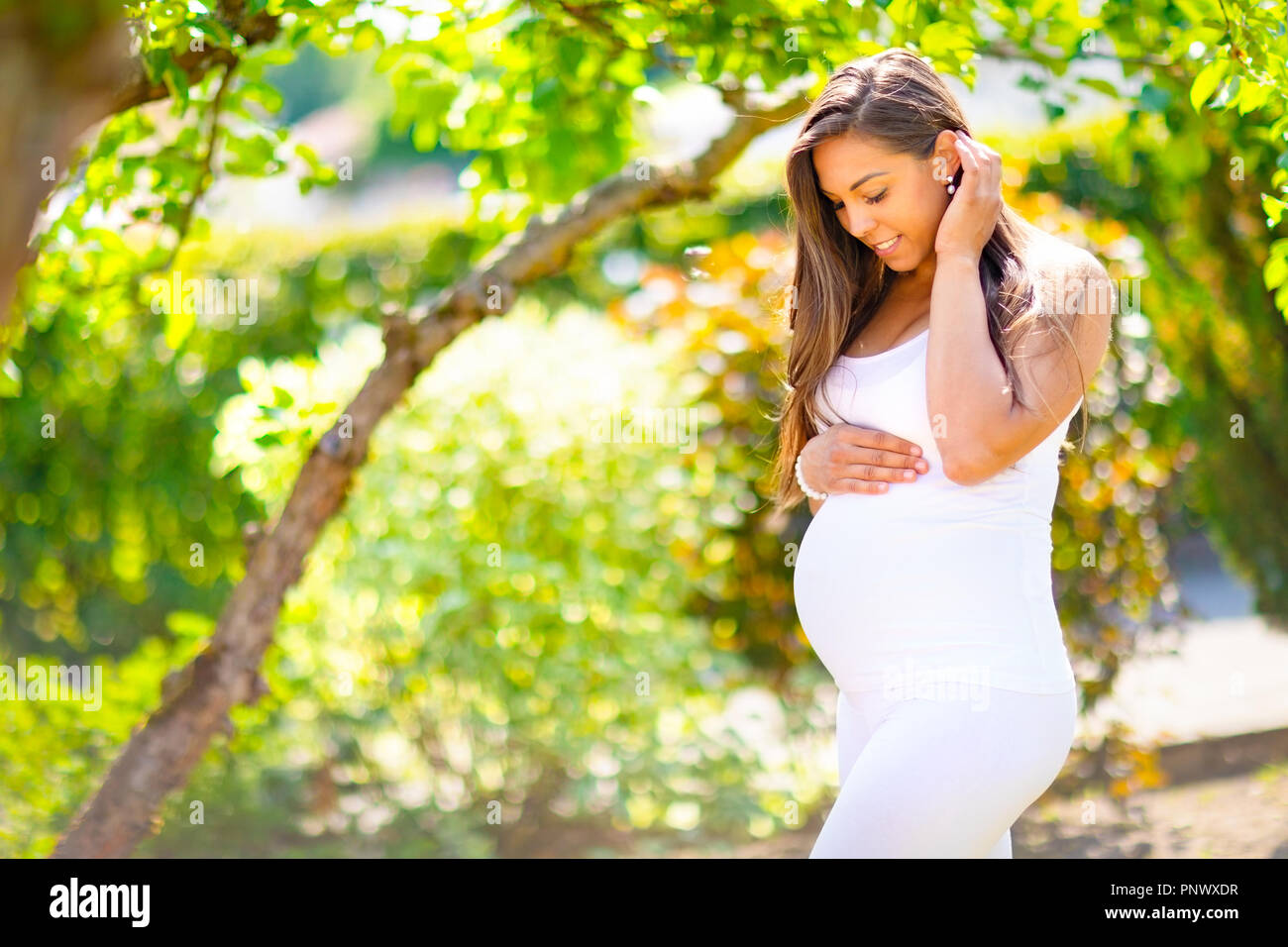 Schwangere Frau im Garten die Hand auf dem Bauch Stockfoto